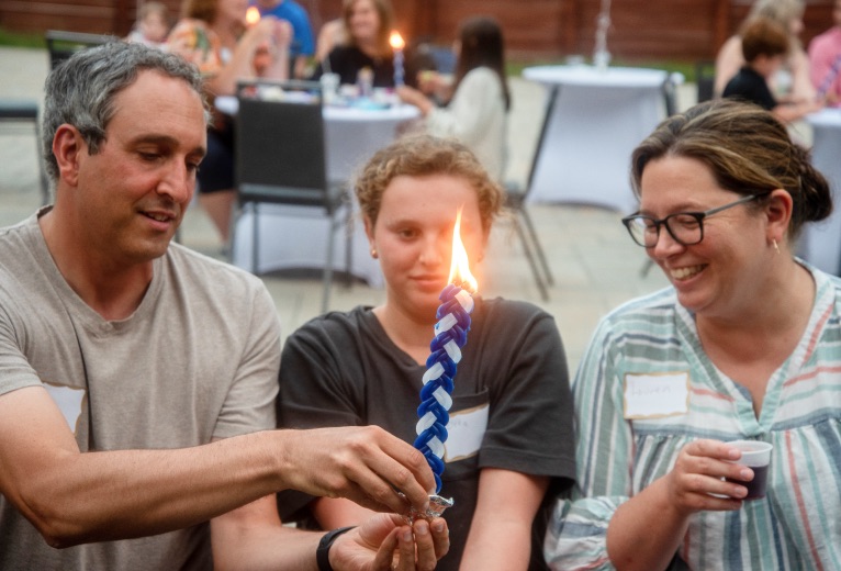 family holding a lit havdalah candle